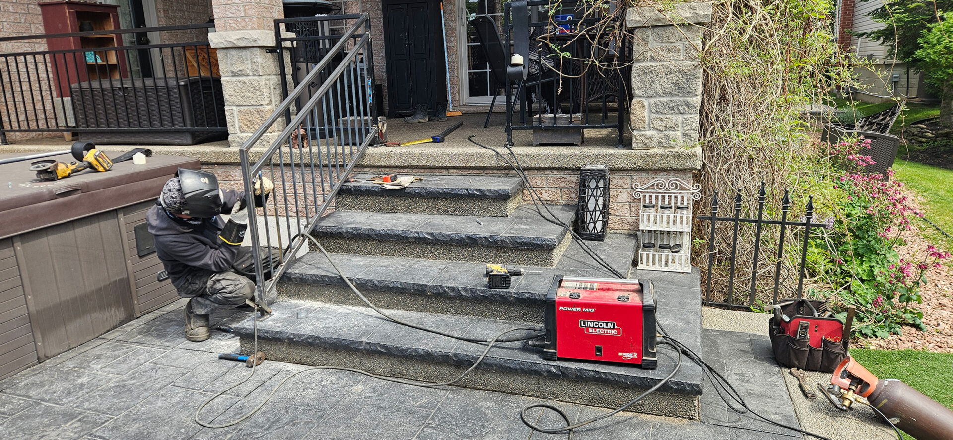 A Welder Welding Stair Railing to Concrete.